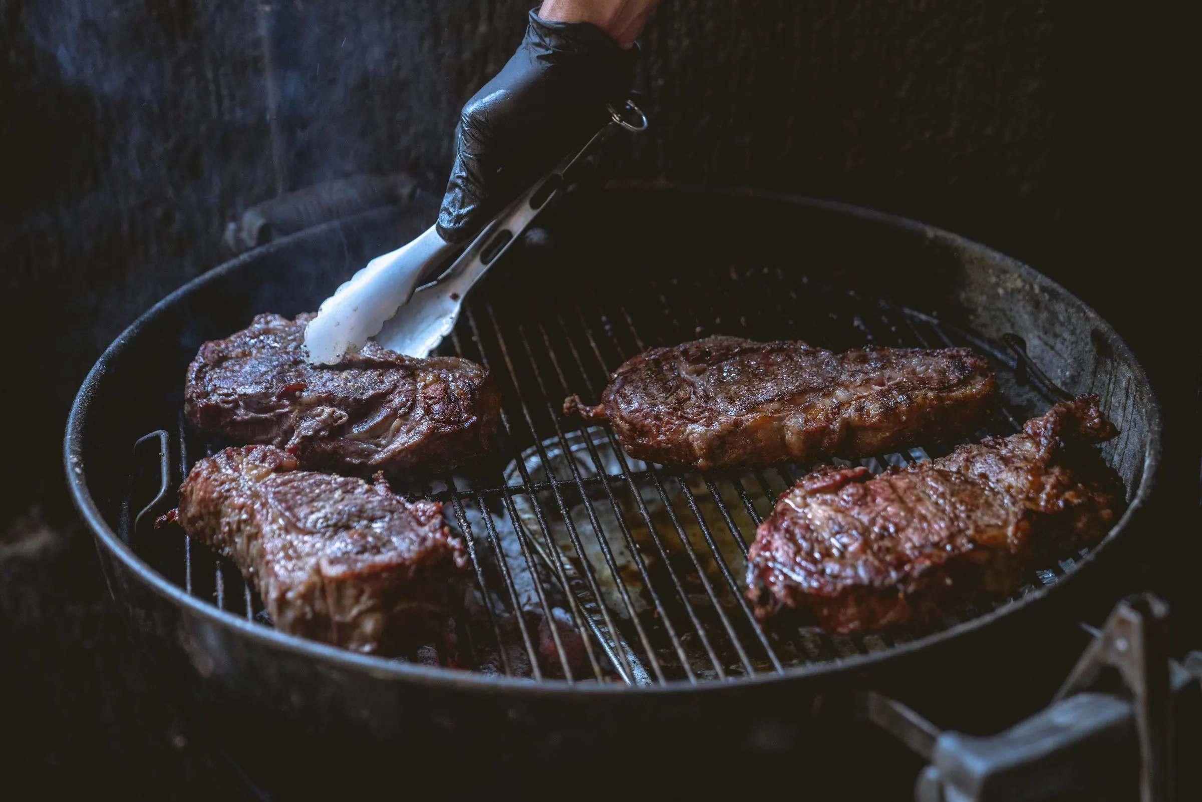 Varias piezas de carne sobre la parrilla de carbón, recién giradas