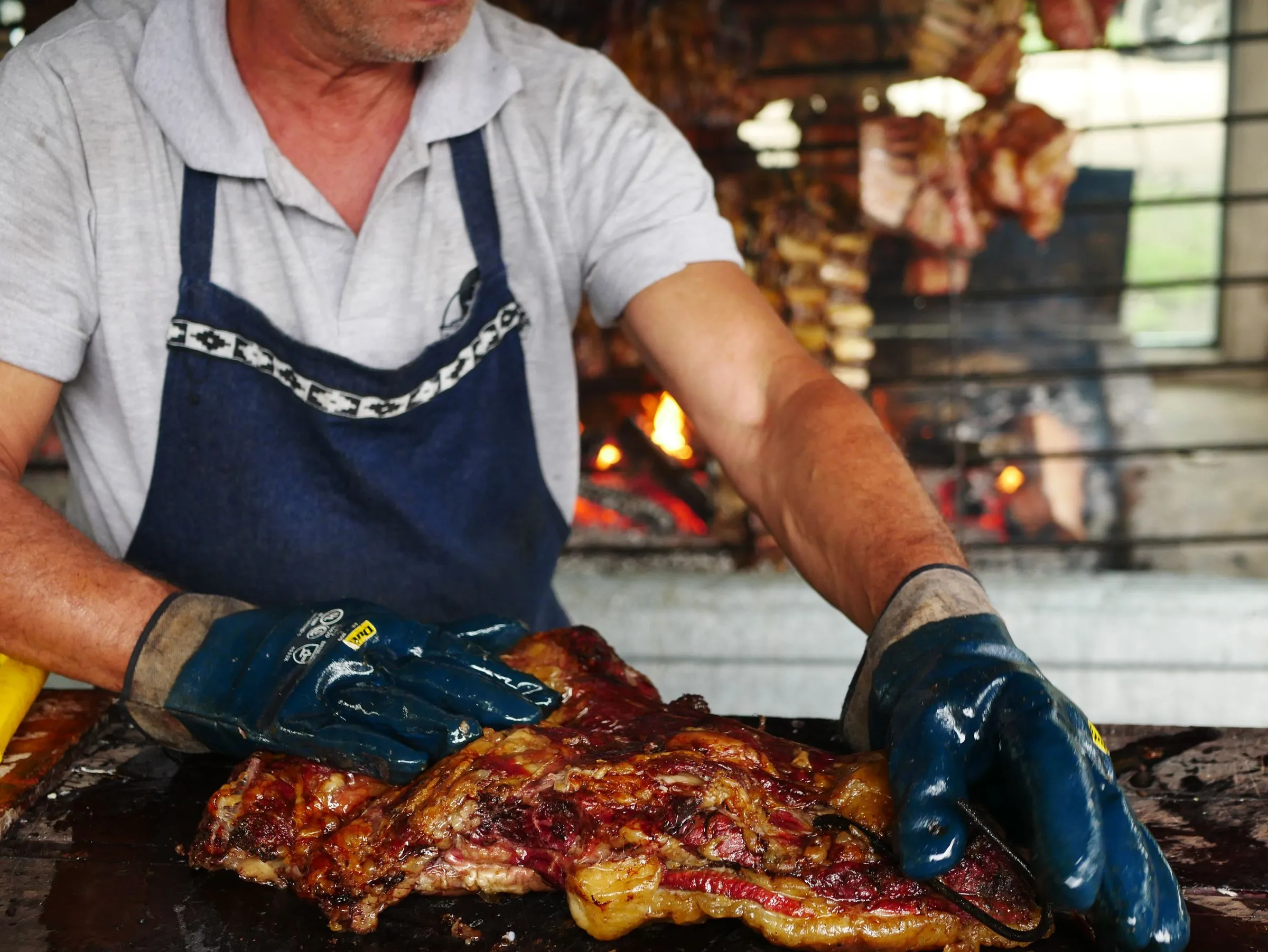 El parrillero de Artebe controlando la brasa con las manos, delantal puesto
